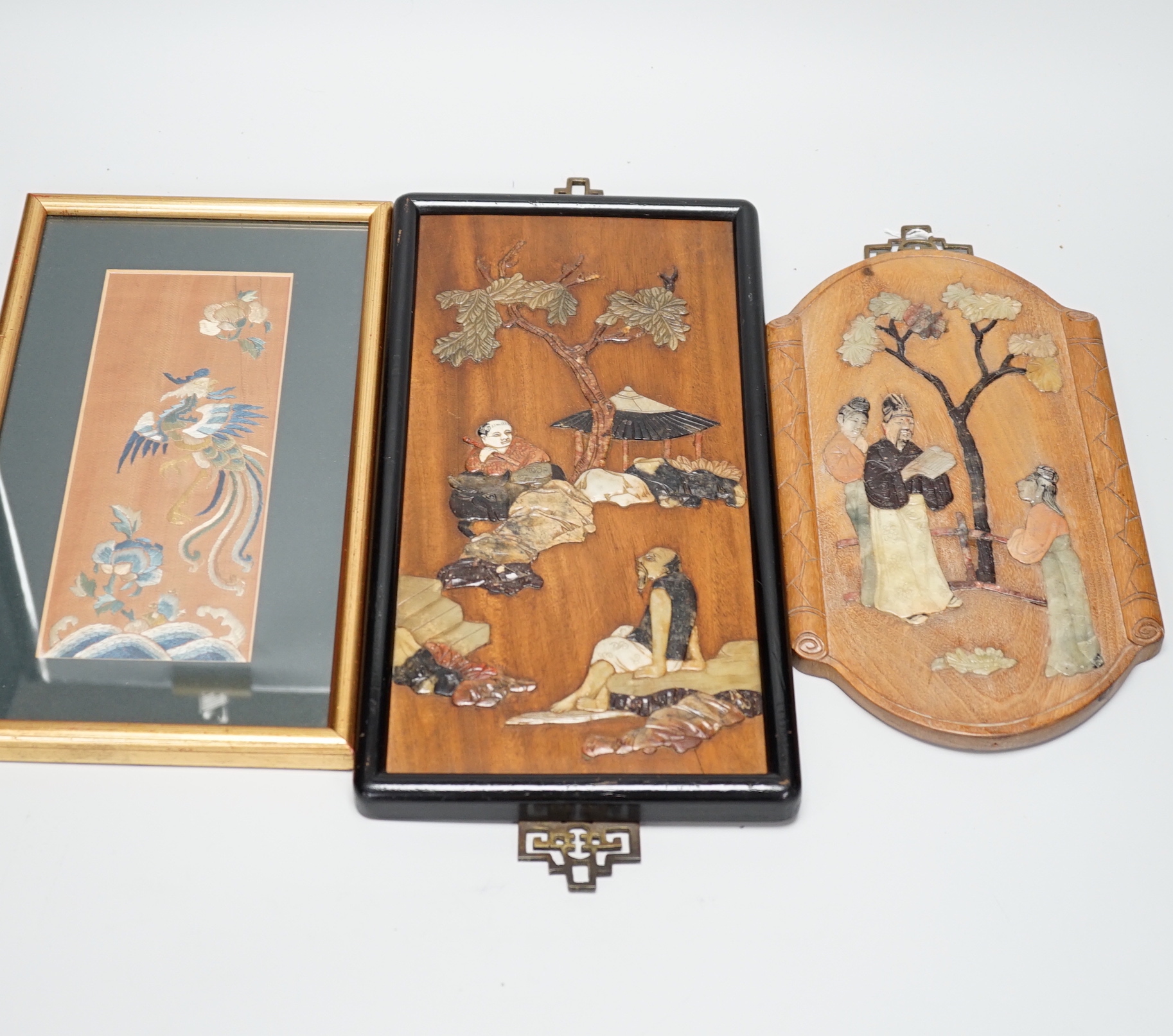 Two Chinese hardwood and mixed soapstone panels and a silk embroidered panel, largest 14.5cm x 29.5cm high